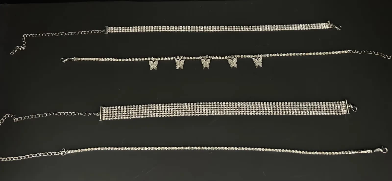 Rhinestone chokers and body chains laid out on a dark surface