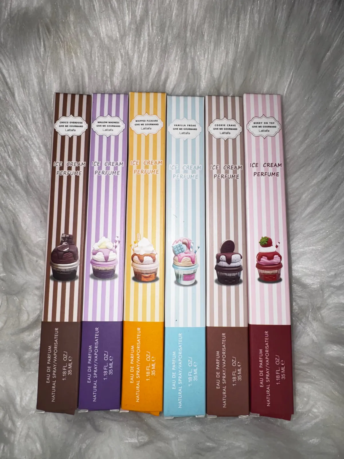 Boxed dessert-scented perfume rollerballs on white fur
